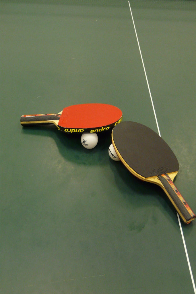Tischtennisschläger und -bälle auf grüner Tischtennisplatte